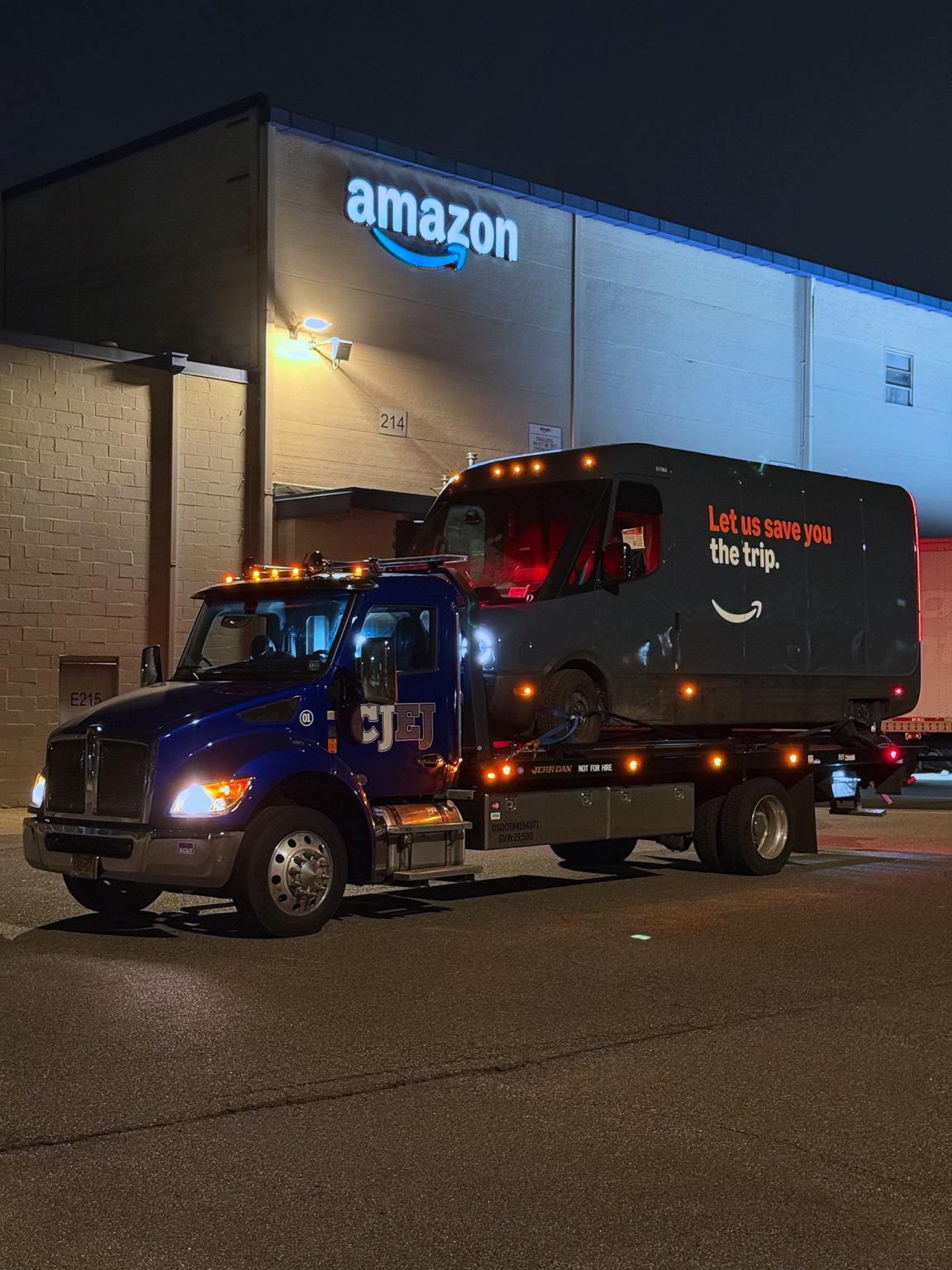 CJEJ flatbed tow truck transporting a delivery van at night